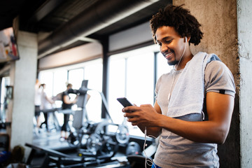 young handsome man using phone while having exercise break in gym