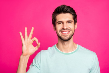 Photo of amazing macho guy showing okey symbol expressing agreement and positive attitude wear casual t-shirt isolated vibrant pink color background