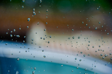 Drops of rain on glass with green tree nature background,romantic shot scene content,colorful raindrops.Blurred leaves of trees