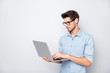 Photo of thoughtful focused clever interested freelancer holding laptop with hands wearing eyeglasses working on deadline project isolated grey color background