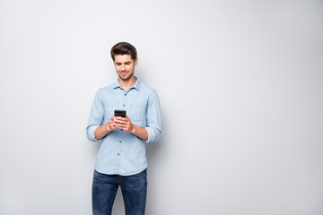portrait of charming focused man stand copyspace using cellphone type message to his online friends 
