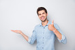 © deagreez - Portrait of positive cheerful man hold hand show thumb-up sign recommend ads display promo wear casual style outfit isolated over grey color background