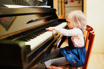 Wall Mural - Adorable little girl playing piano