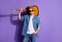 Photo Of Confident Attractive Handsome Man Wearing Brown Cap Spectacles Standing With Guitar On His Shoulder And Hand In Pocket Isolated Over Purple Vibrant Color Background