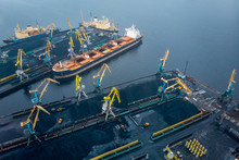 Loading Coal Anthracite Mining In Port On Cargo Tanker Ship With Crane Bucket Of Train. Aerial Top View
