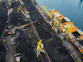 Wall Mural - Loading coal anthracite mining in port on cargo tanker ship with crane bucket of train. Aerial top view