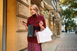 © Anton - Attractice excited styliah blond girl thoughtfully looking in shopping bag on street