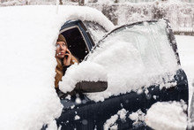 Young Woman Calling For Help Or Assistance Inside Snow Covered Car.  Engine Start In Frost. Breakdown Services In The Winter.