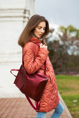 Poster - Young stylish woman in a salmon down jacket posing on a background of autumn park