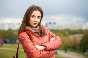 Poster - Young stylish woman in a salmon down jacket posing on a background of autumn park