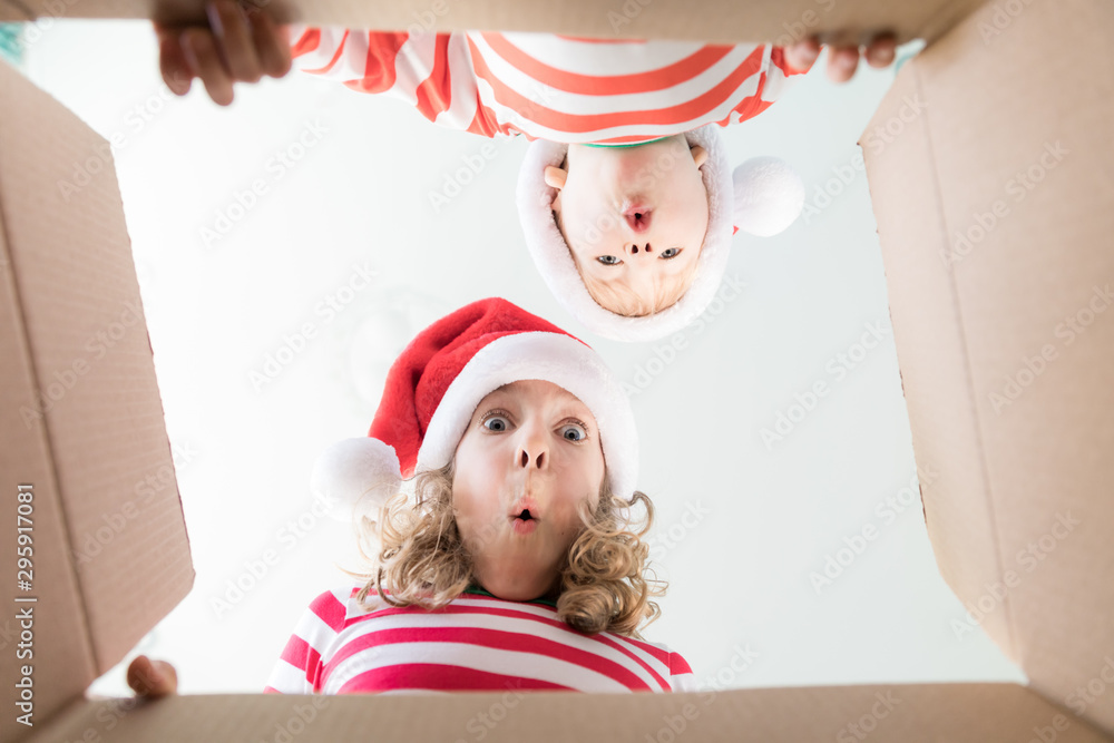 Surprised children unpack Christmas gift box - obrazy, fototapety, plakaty 