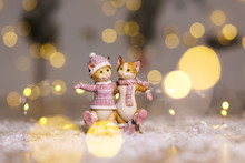 Decorative Figurines Of A Christmas Theme. Figurine Of Cute Hugging Cats Dressed In A Knitted Sweater, Scarf And Hat. Christmas Tree Decoration. Festive Decor, Warm Bokeh Lights.