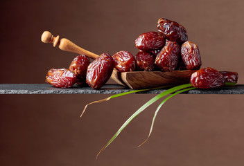  Closeup sweet dried dates in wooden dish.