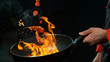 Closeup of chef holding wok pan with falling prawn