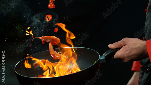 Cuadros en Lienzo Closeup of chef holding wok pan with falling prawn
