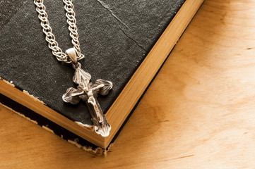 Holy bible with silver cross on wooden background