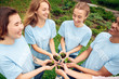 © Viktoriia - Volunteering. Young people volunteers outdoors together holding trees seedlings hands top view laughing cheerful