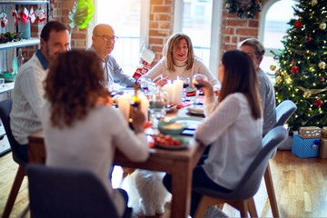 Family and friends dining at home celebrating christmas eve with traditional food and decoration, all sitting on the table together