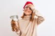 © Krakenimages.com - Beautiful redhead woman wearing christmas hat holding cookies jar over isolated background stressed with hand on head, shocked with shame and surprise face, angry and frustrated. Fear