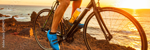 Fotografía Bike race at sunset road biking cyclist riding bicycle outdoor with sun flare closeup of legs and blue professional clip shoes banner panorama