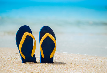 Flip flops on the white sand beach with blue sea background