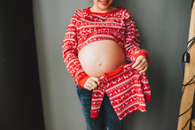 Pregnant Caucasian Woman Holding A Little Christmas Baby Sweater