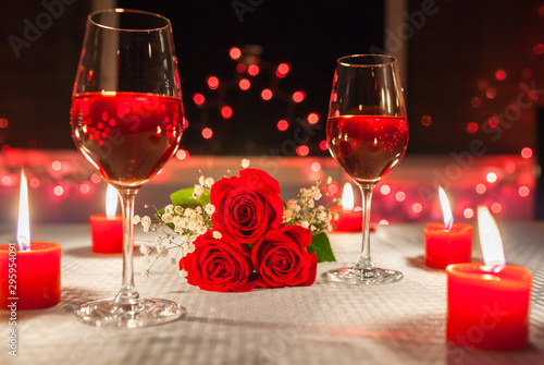 Romantic date night. Candle light dinner with roses and wine.
