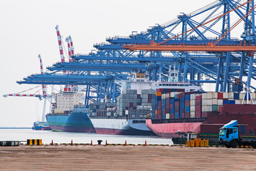 The cargo ship industry is parked in a harbor with a large crane bridge, transporting goods, importing and exporting trucks