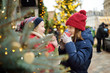 © MNStudio - Two adorable sisters drinking hot chocolate on traditional Christmas fair in Riga, Latvia. Children enjoying sweets, candies and gingerbread on Xmas market.