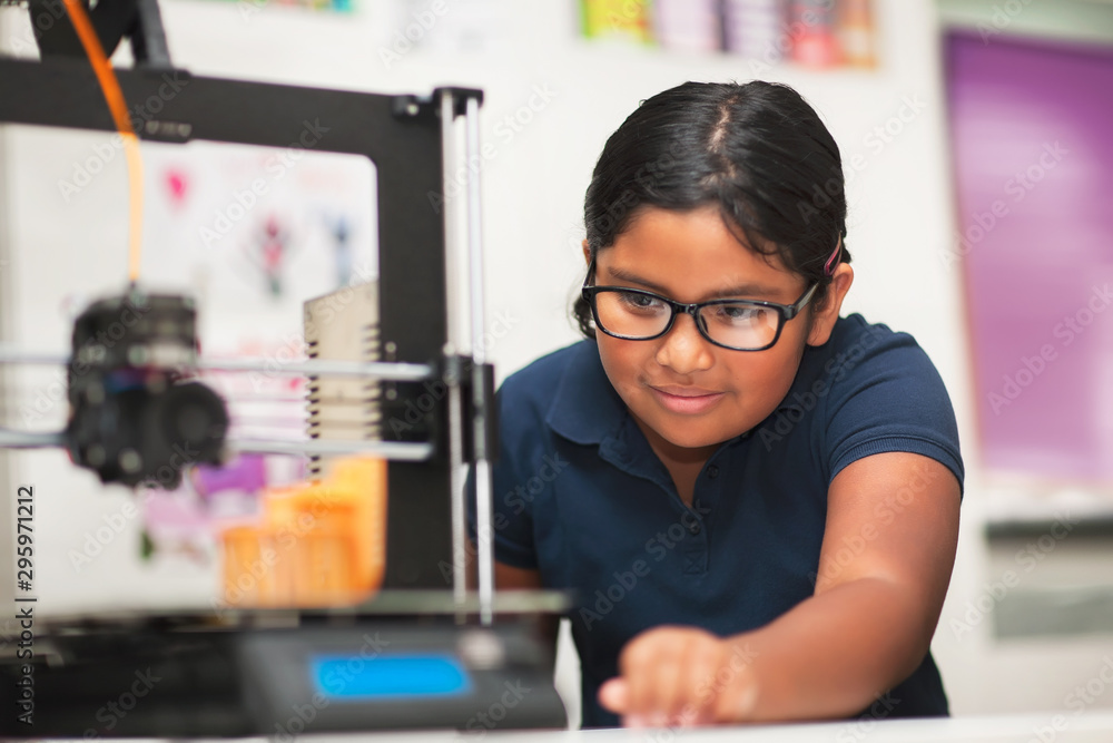 A female student in a modern classroom observing the printing process ...