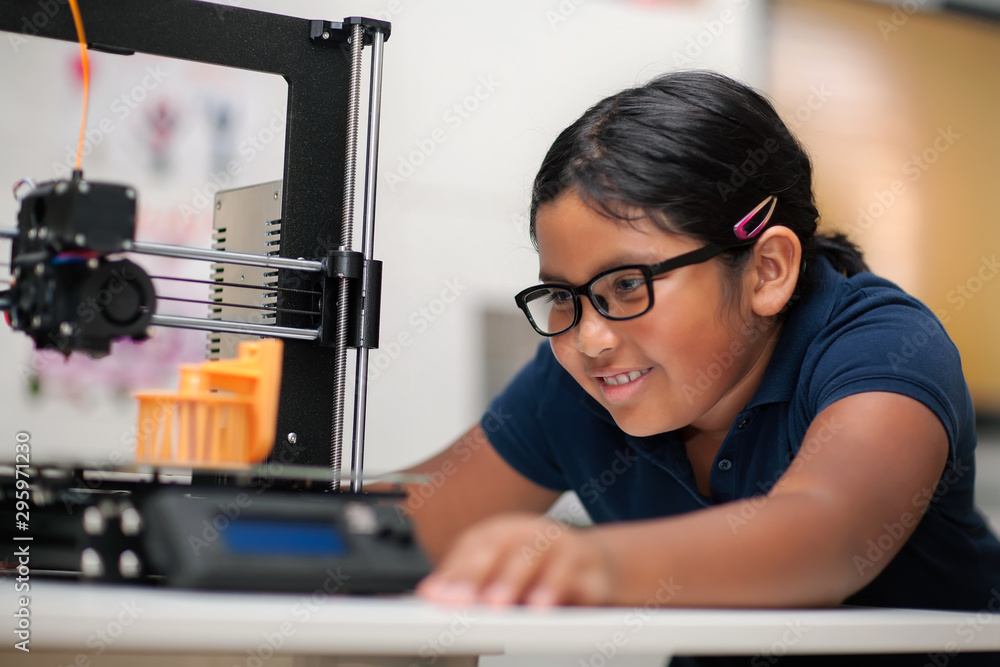 A happy young girl wearing glasses and watching a 3d printer finish the 3d model she created. - obrazy, fototapety, plakaty 