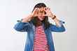 © Krakenimages.com - Young chinese woman wearing striped t-shirt and denim shirt over isolated white background Doing heart shape with hand and fingers smiling looking through sign