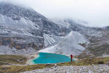 Wall Mural - traveler taking photo of lake and mountain landscape in cloudy day at yading in china. travel lifest