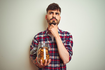 Sticker - Young man wearing bathrobe drinking cup of coffee standing over isolated white background serious face thinking about question, very confused idea