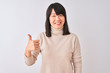 © Krakenimages.com - Young beautiful chinese woman wearing turtleneck sweater over isolated white background doing happy thumbs up gesture with hand. Approving expression looking at the camera showing success.