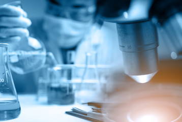 lab technician assistant analyzing a blood sample in test tube at laboratory with microscope. Medical, pharmaceutical and scientific research and development concept.