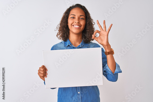 Fotografía Young brazilian woman holding banner standing over isolated white background doi