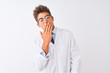 © Krakenimages.com - Young handsome sciencist man wearing glasses and coat over isolated white background bored yawning tired covering mouth with hand. Restless and sleepiness.