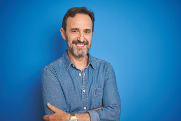 Poster - Handsome middle age senior man with grey hair over isolated blue background happy face smiling with crossed arms looking at the camera. Positive person.