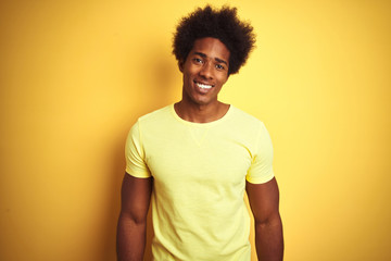 Poster - African american man with afro hair wearing t-shirt standing over isolated yellow background with a happy and cool smile on face. Lucky person.