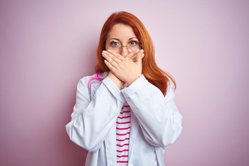 Canvas Print - Young redhead doctor woman wearing glasses over pink isolated background shocked covering mouth with hands for mistake. Secret concept.