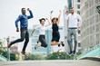 © DragonImages - Happy excited multi-ethnic business people jumping in the air when standing on city road