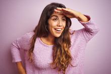 Young Beautiful Woman Wearing Sweater Standing Over Pink Isolated Background Very Happy And Smiling Looking Far Away With Hand Over Head. Searching Concept.