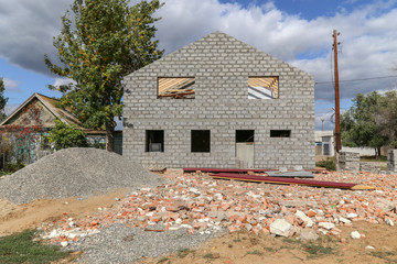 The construction of a two-story house in the village. Gray stone, gravel.