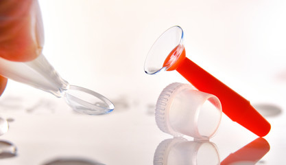 Wall Mural - Fingers catching a contact lens and an applicator on table