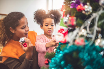 Merry Christmas and Happy Holiday. Mom and daughter decorate the Christmas tree . The morning before Xmas. .Happy little smiling girl .