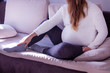 Pregnant woman massaging a swollen foot. Swelling in pregnancy. Swollen legs. Pregnant woman sitting on the sofa.