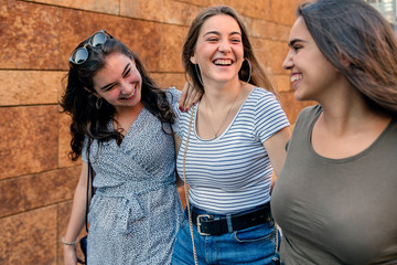 Close up of a group of three female friends walking in the street