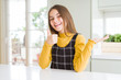 © Krakenimages.com - Young beautiful blonde kid girl wearing casual yellow sweater at home Showing palm hand and doing ok gesture with thumbs up, smiling happy and cheerful