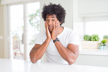 Poster - Young african american man wearing casual white t-shirt sitting at home Tired hands covering face, depression and sadness, upset and irritated for problem